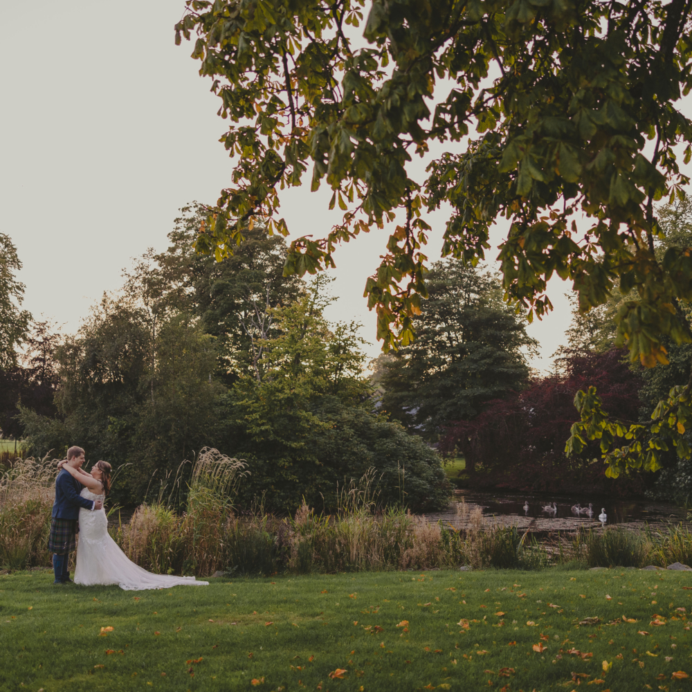 Bride and groom beside a lake at Meldrum House Hotel