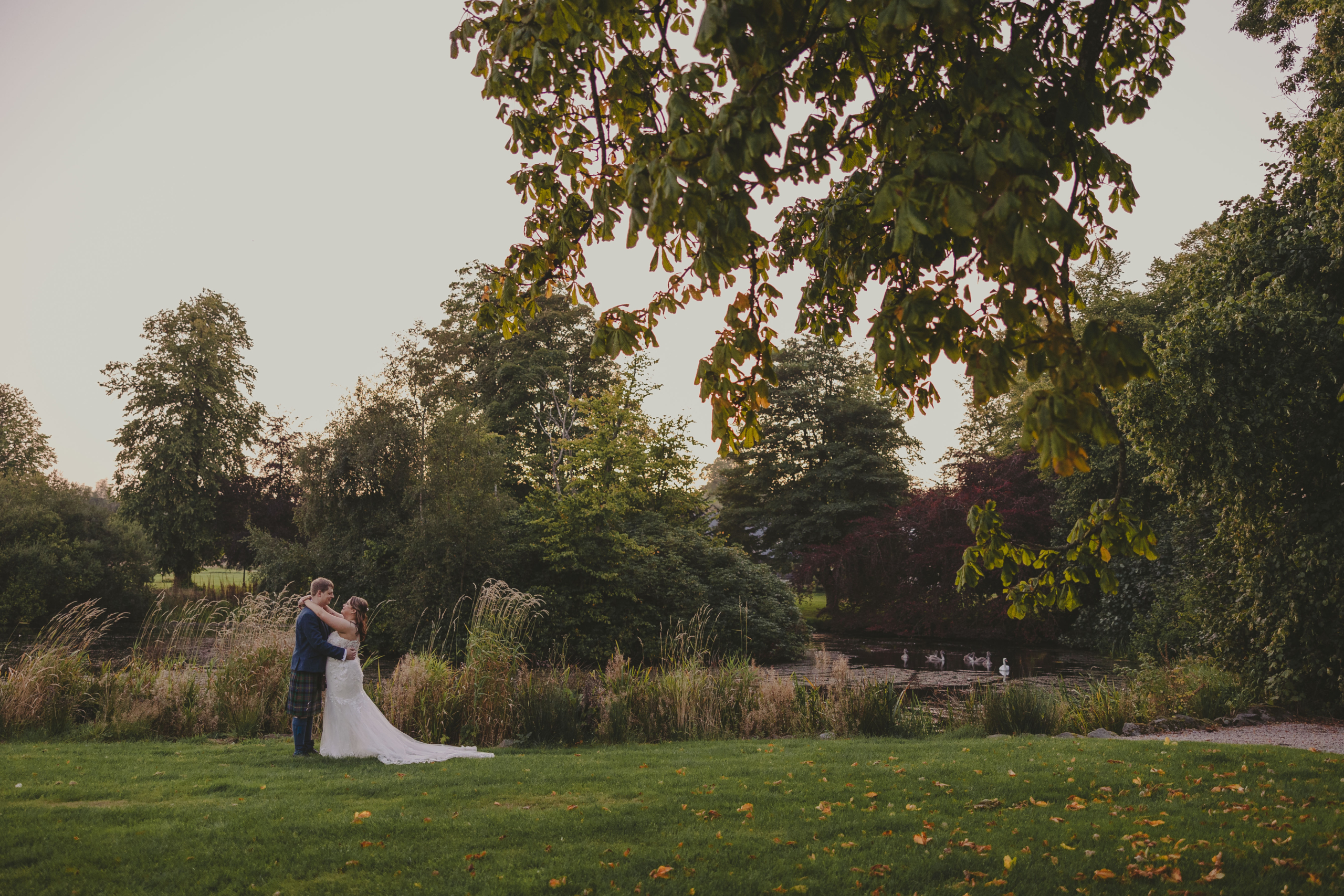 Bride and groom beside a lake at Meldrum House Hotel